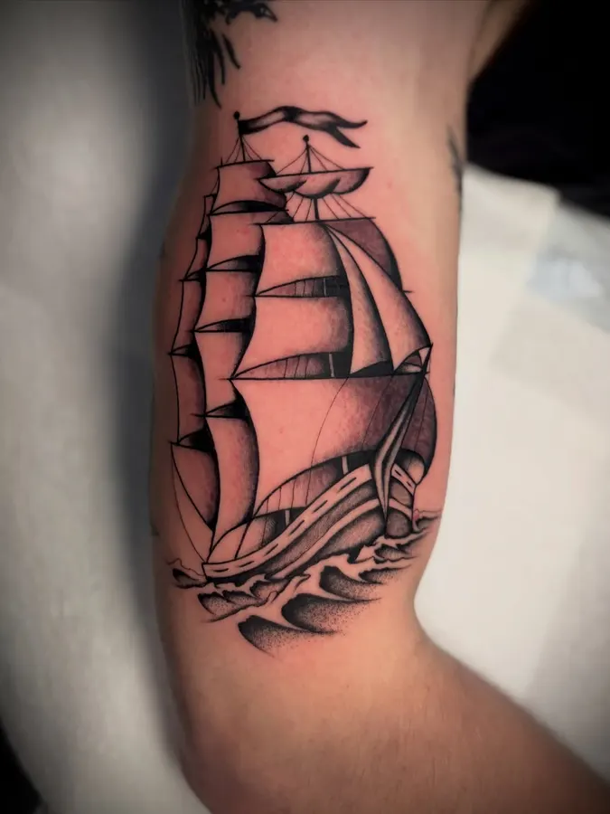Traditional sailing ship tattooed on a forearm.