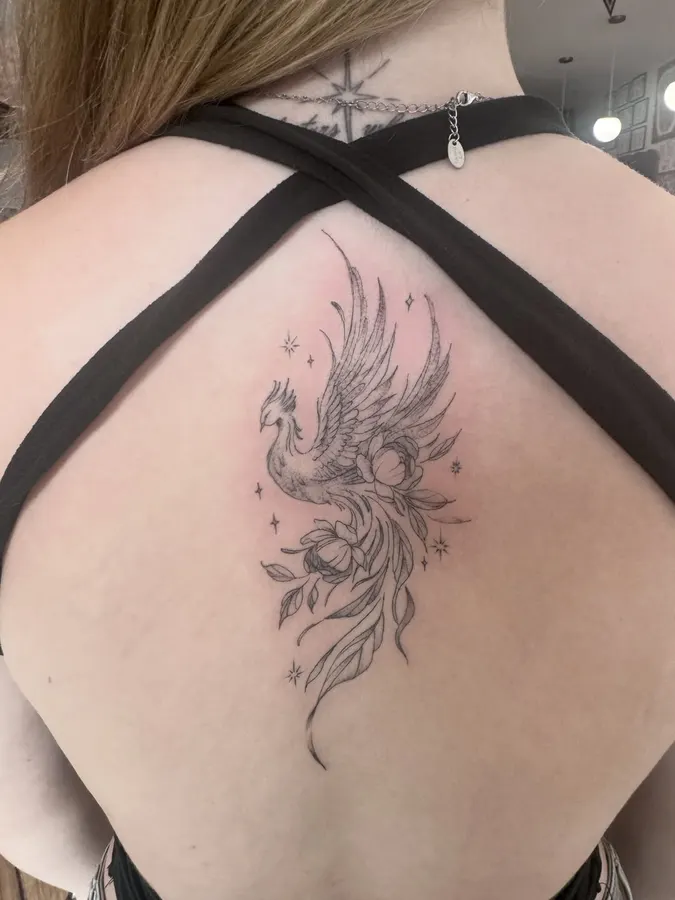 Oiseau et feuillage tatoués avec un trait fin.