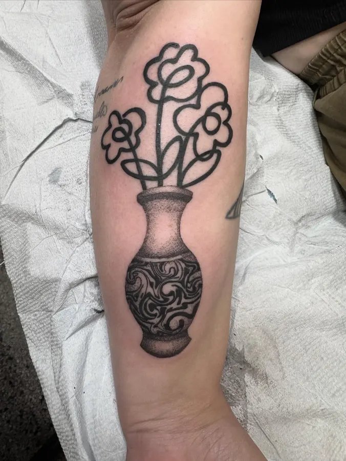 Vase ornemental et fleurs en lignes noires.