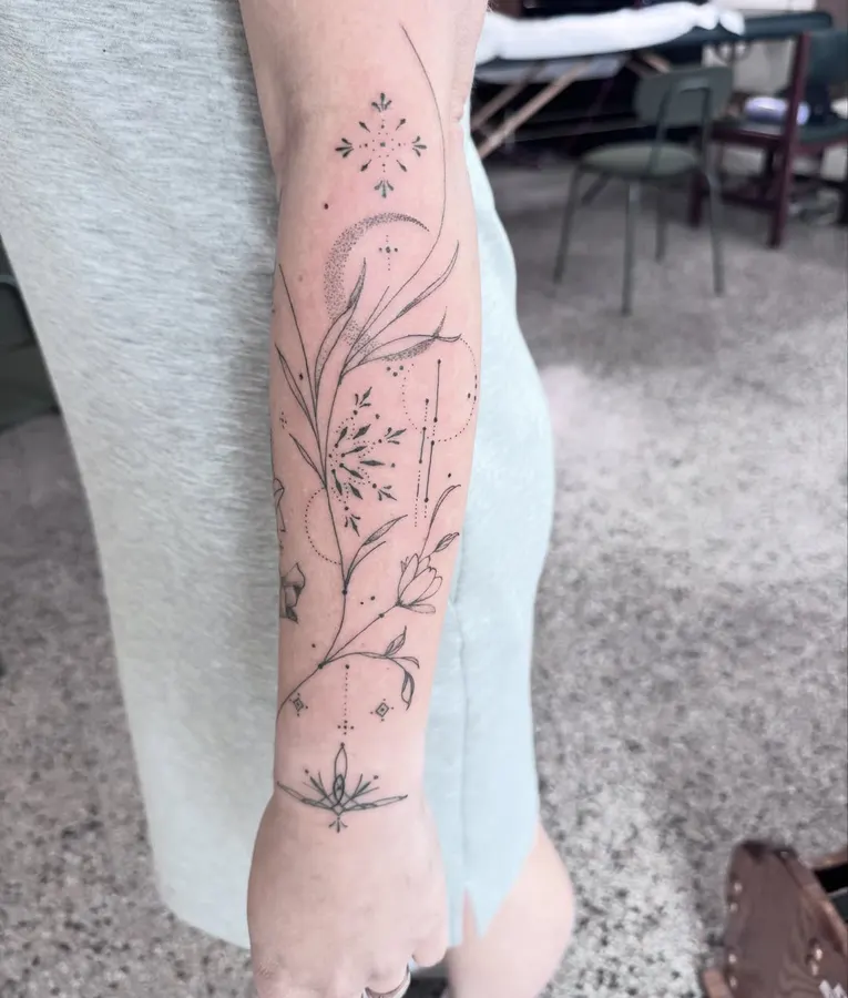 Branche botanique délicate tatouée sur un bras.